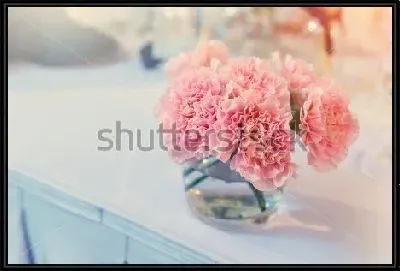 Букетик розовых гвоздик в стеклянном стакане на белой столешнице