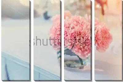 Букетик розовых гвоздик в стеклянном стакане на белой столешнице