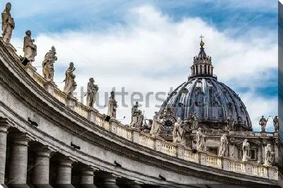 Вид на колоннады со скульптурами и купол собора Святого Петра в Ватикане на фоне неба с облаками