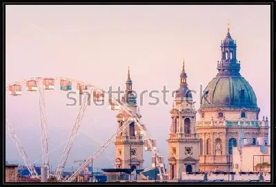 Городской пейзаж Будапешта с колесом обозрения на фоне куполов Базилики Святого Иштвана на розовом закатном небе