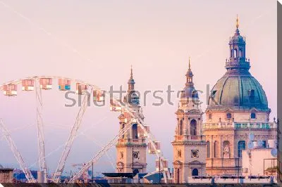 Городской пейзаж Будапешта с колесом обозрения на фоне куполов Базилики Святого Иштвана на розовом закатном небе
