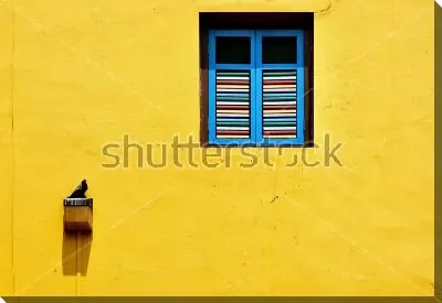 Яркие голубые ставни на яркой жёлтой стене с птицей