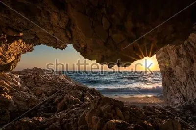 Плакат Чудесный вид на восход над морем из скалистой пещеры