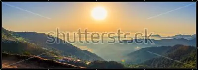 Картина Красивый панорамный пейзаж с облаками на горных вершинах и большим солнцем