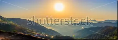 Постер Красивый панорамный пейзаж с облаками на горных вершинах и большим солнцем