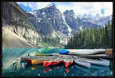 Разноцветные байдарки на пристани у озера Морейн на фоне величественных скалистых гор и хвойного леса в Национальном парке Банф (Канада)