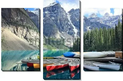 Разноцветные байдарки на пристани у озера Морейн на фоне величественных скалистых гор и хвойного леса в Национальном парке Банф (Канада)