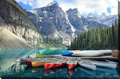 Постер Разноцветные байдарки на пристани у озера Морейн на фоне величественных скалистых гор и хвойного леса в Национальном парке Банф (Канада)