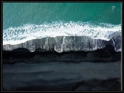 Зелёная волна на пляже Рейнисфьяра с чёрным песком с высоты птичьего полёта (Исландия)