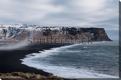 Суровый великолепный пейзаж с прибоем на пляже с чёрным песком на фоне горных хребтов (Исландия)