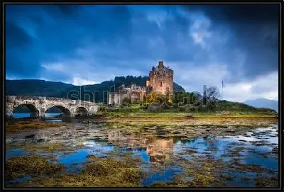 Картина Замок Эйлен-Донан с арочным мостом через реку на фоне хмурого неба (Шотландия)