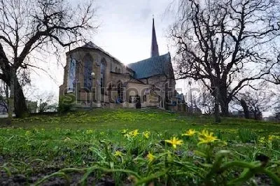 Мистический пейзаж с собором Хагачуркан в окружении деревьев и жёлтыми первоцветами на первом плане (Гётеборг, Швеция)