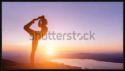 Девушка стоит на одной ноге в позе йоги на фоне красивого заката над озером и горной долиной