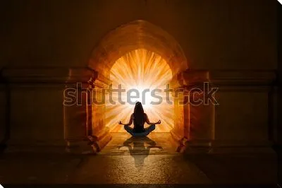 Девушка в позе лотоса медитирует под красивой восточной аркой на фоне золотого сияния