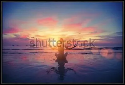 Девушка в позе лотоса медитирует на побережье океана в лучах фантастического заката