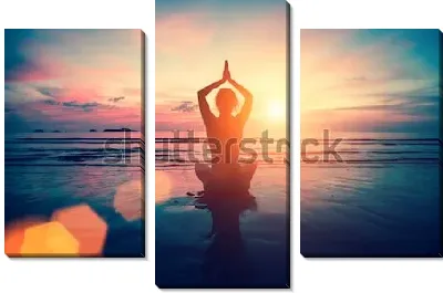 Девушка занимается йогой на берегу океана в лучах розово-золотого заката