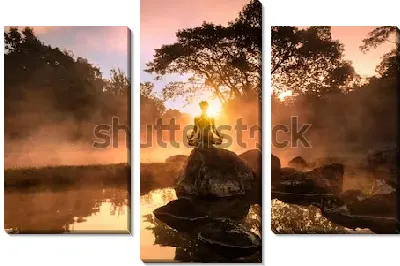 Силуэт медитирующего человека на большом камне на фоне великолепного утреннего пейзажа на берегу туманного озера