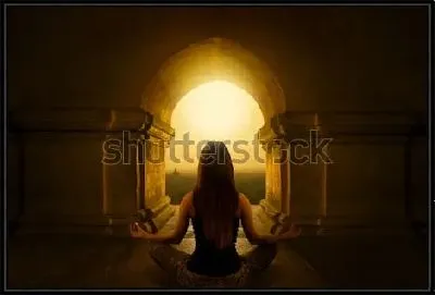 Девушка медитирует в позе лотоса под сводом арки  буддийского  храма на восходе солнца