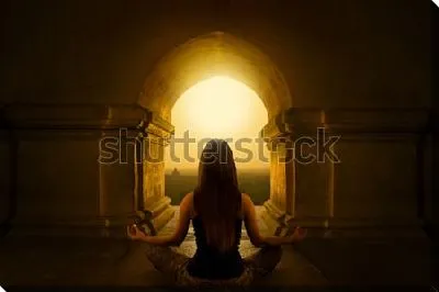 Девушка медитирует в позе лотоса под сводом арки  буддийского  храма на восходе солнца