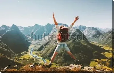 Счастливый путешественник с рюкзаком радуется покорению горной вершины и любуется великолепным видом на каьон