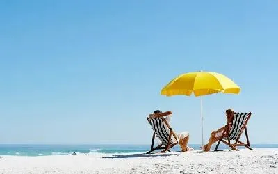 Плакат Мужчина и девушка в шезлонгах и под зонтом на морском берегу