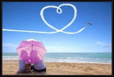 Мужчина и женщина под зонтом на берегу моря на фоне летящего самолёта вырисовывающего сердце