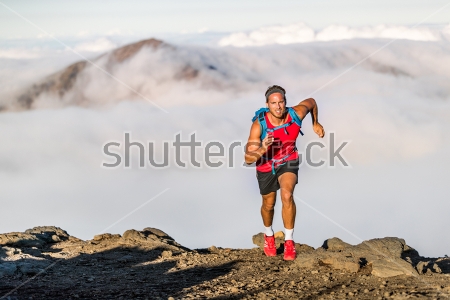 Постер Бегун тренирует свою выносливость на сложной трассе в горах над облаками 