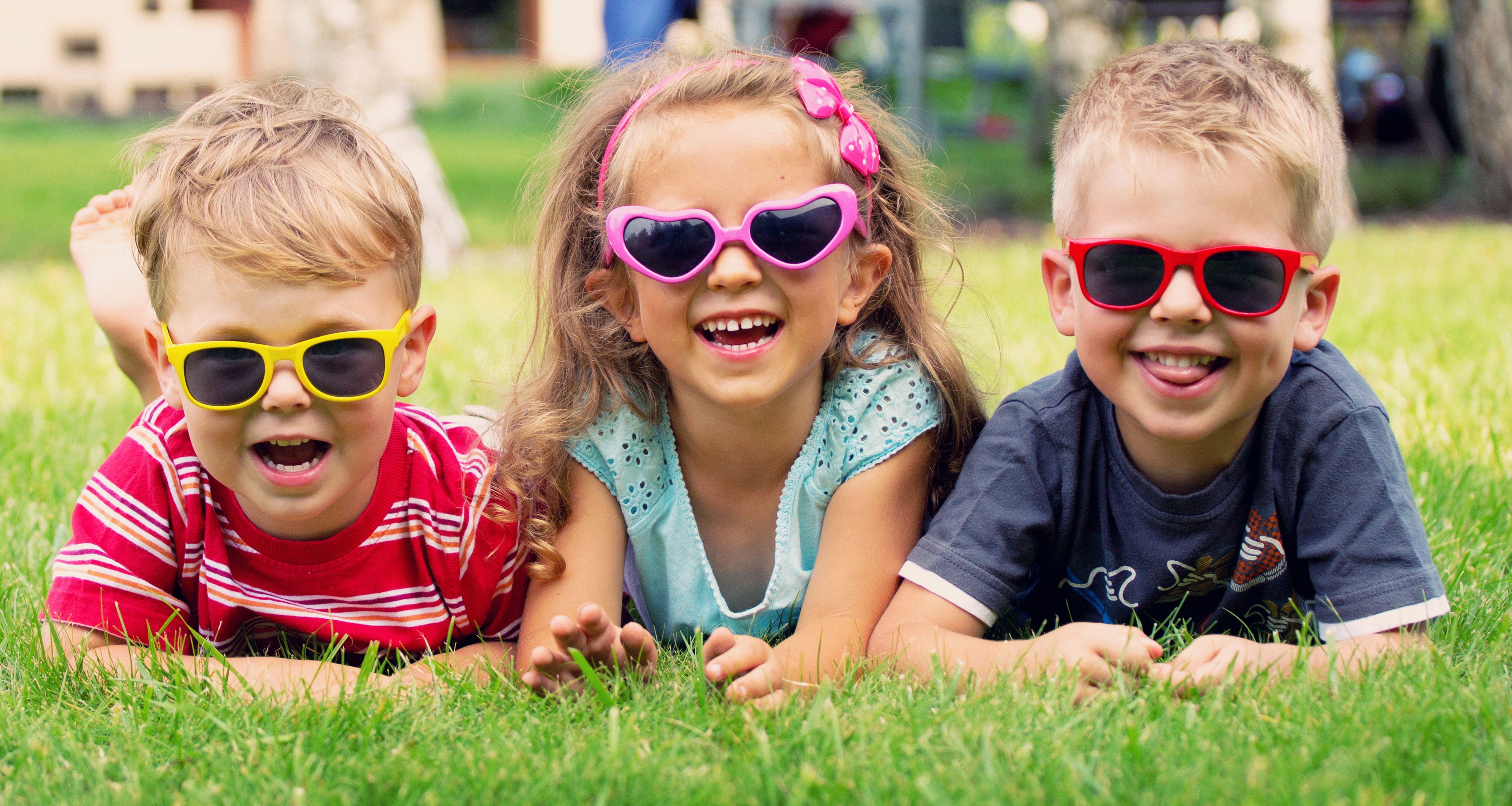 Девочка улыбается мальчику. Счастливый ребенок. Ребенок в солнечных очках. Веселые дети. Детские солнцезащитные очки.