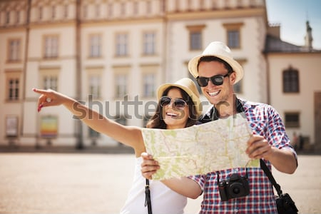 Постер Счастливые туристы с картой любуются достопримечательностями города  