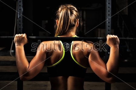 Картина Девушка с мускулистым телом выполняет силовые упражнения со штангой - вид со спины 
