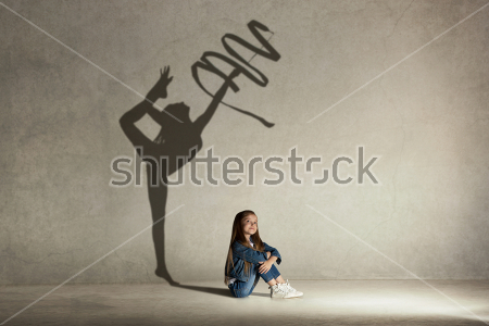 Картина Девочка мечтает стать гимнасткой - сидящая фигурка девочки на фоне стены с тенью гимнастки с лентой 