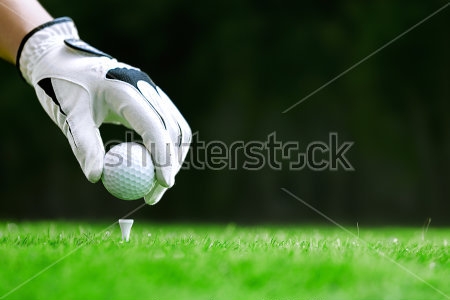 Картина Рука в перчатке ставит мяч для гольфа на столбик в траве 