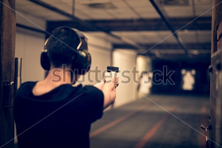 Картина Мужчина целится из пистолета по мишеням в помещении 