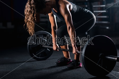Картина Девушка на силовой тренировке готовится поднять штангу 