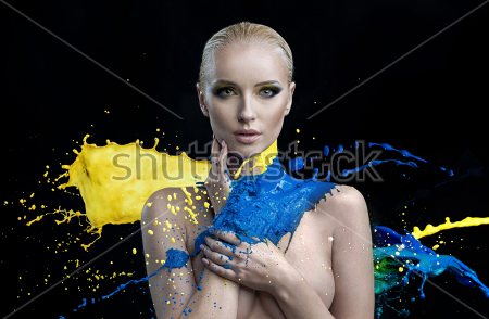 Картина Портрет обнажённой девушки, облитой всплесками жёлтой и синей краски на чёрном фоне 