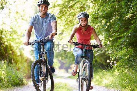 Картина Счастливая молодая пара на велосипедах в зелёном парке 