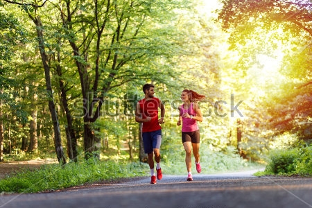 Постер Молодая симпатичная пара на пробежке в зелёном парке 