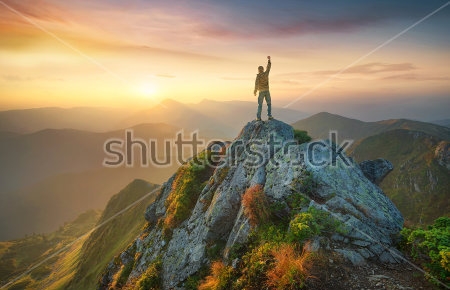 Постер Турист на вершине скалы на фоне прекрасного горного пейзажа в лучах закатного солнца  