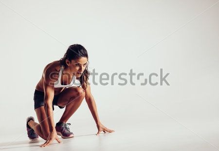 Постер Спортсменка бегунья в низкой позиции готовится к старту 