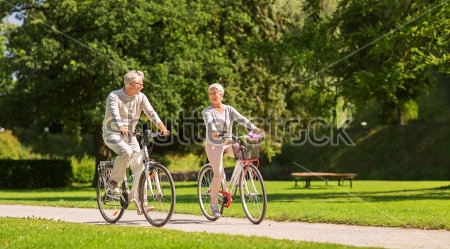 Постер Счастливая пара почтенного возраста на велосипедах в летнем парке  